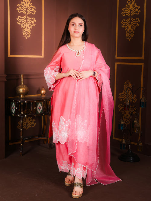 Woman in a pink traditional outfit standing in a decorated room.