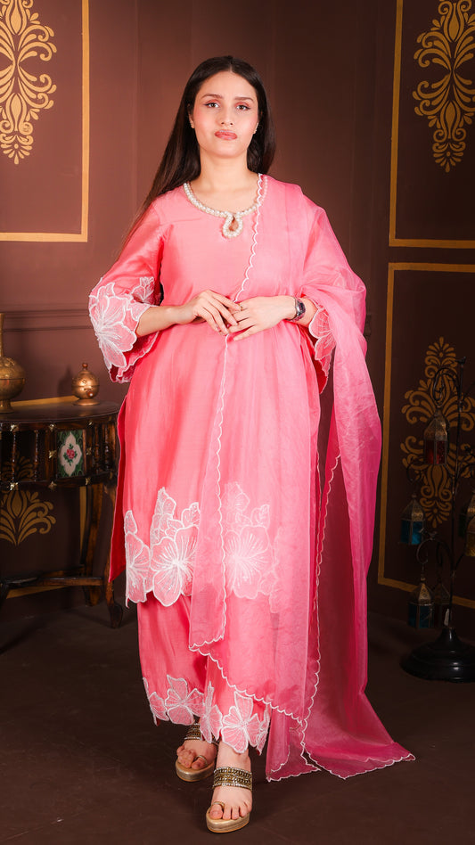 Woman in a pink traditional outfit standing in a decorated room.